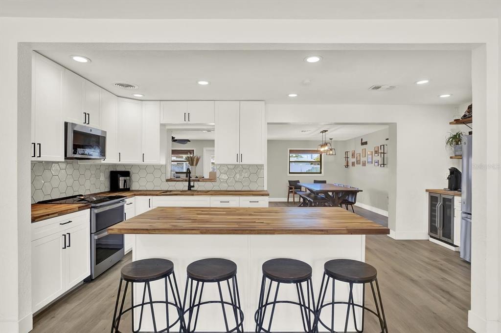6060 39th Avenue North St. Petersburg, FL 33709 - Photo 6 of 29 a large kitchen with granite countertop a stove a sink a refrigerator and white cabinets with wooden floor
