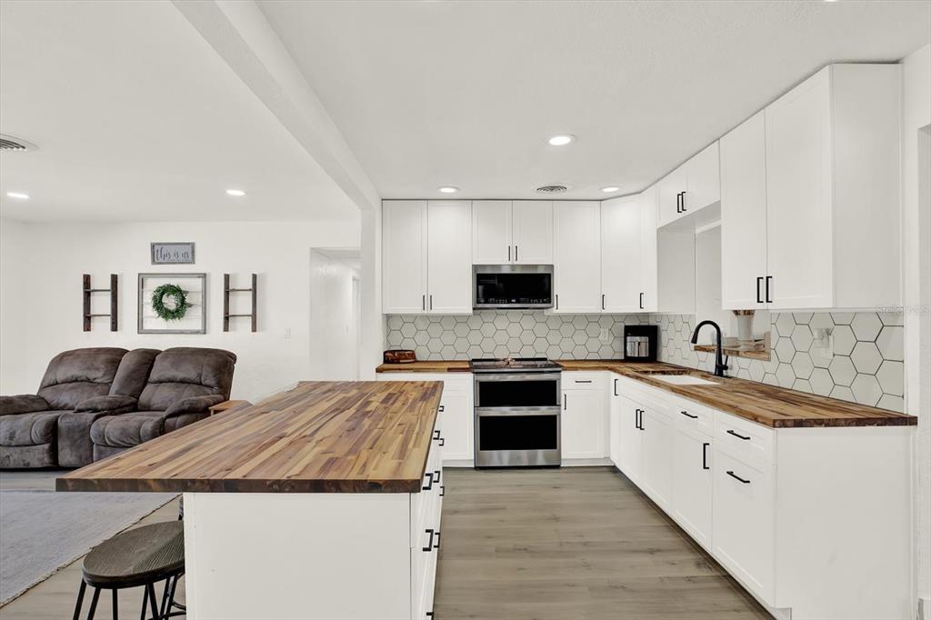 6060 39th Avenue North St. Petersburg, FL 33709 - Photo 8 of 29 a large kitchen with granite countertop a stove top oven a sink a dining table and chairs