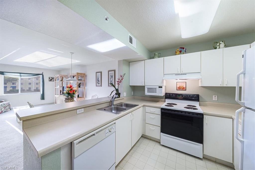 8288 Key Royal Lane, Unit 1424 Naples, FL 34119 - Photo 4 of 13 a kitchen with a sink stove and white cabinets