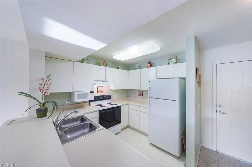 8288 Key Royal Lane, Unit 1424 Naples, FL 34119 - Photo 5 of 13 a kitchen with a refrigerator a stove and white cabinets