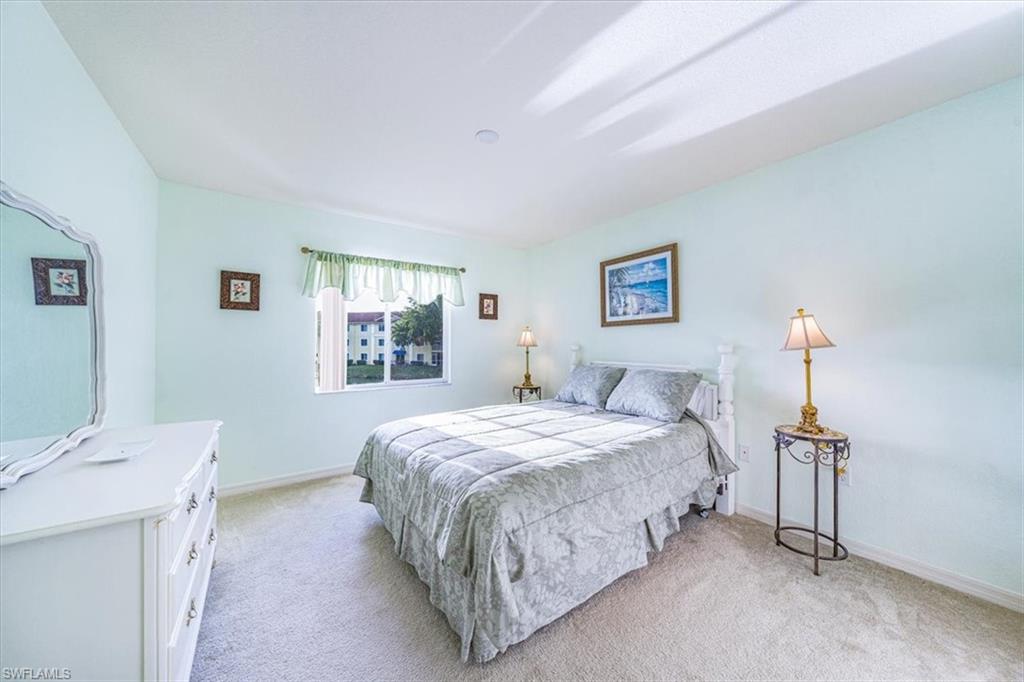 8288 Key Royal Lane, Unit 1424 Naples, FL 34119 - Photo 9 of 13 a bedroom with a bed and a table