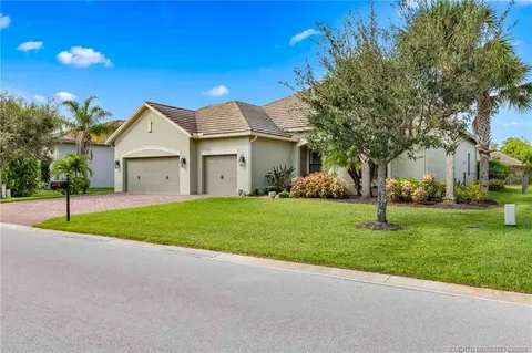 a view of a house with a big yard and palm trees