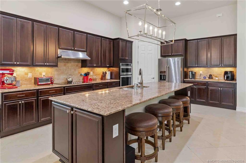 1092 Southwest Scrub Oak Avenue Palm City, FL 34990 - Photo 18 of 45 a kitchen with stainless steel appliances a table chairs microwave and refrigerator