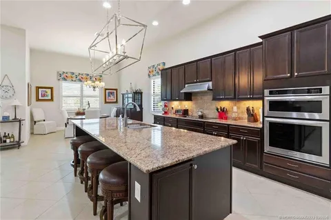 a kitchen with stainless steel appliances a table chairs microwave and refrigerator