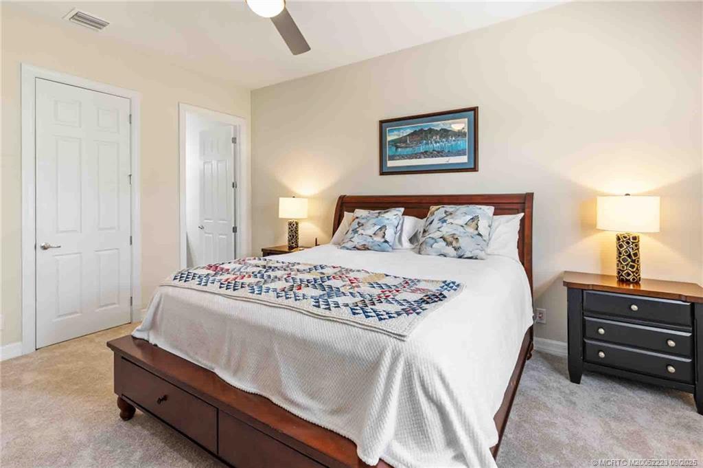 1092 Southwest Scrub Oak Avenue Palm City, FL 34990 - Photo 28 of 45 a bedroom with a bed and a lamp on dresser