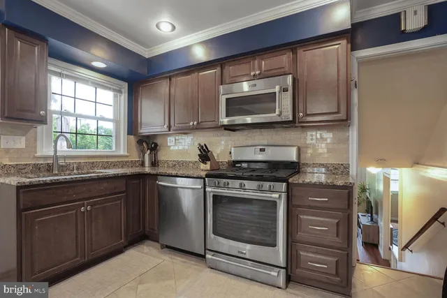a kitchen with stainless steel appliances granite countertop a stove top oven a sink and a microwave