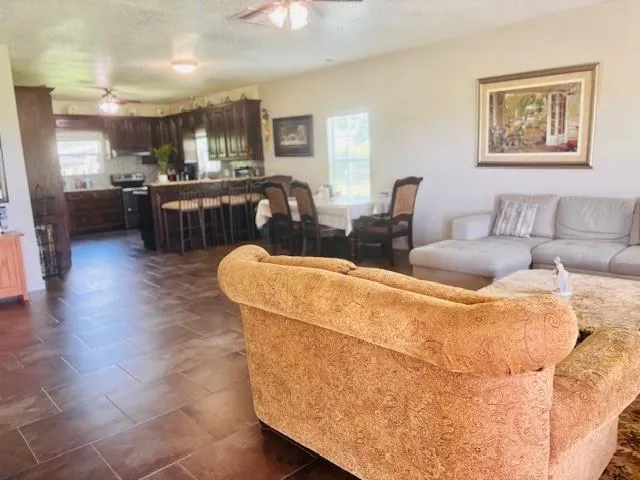 a living room with couches and kitchen view with wooden floor