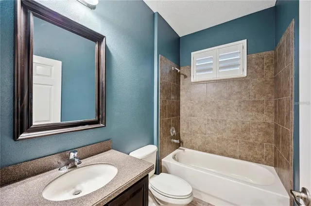 a bathroom with a granite countertop sink toilet a mirror and bathtub