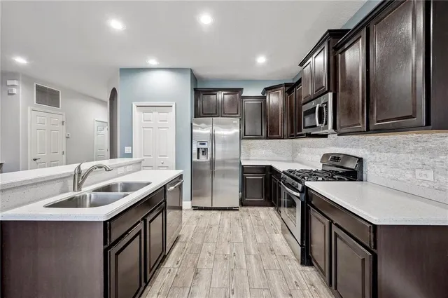 a kitchen with stainless steel appliances granite countertop a sink stove and refrigerator