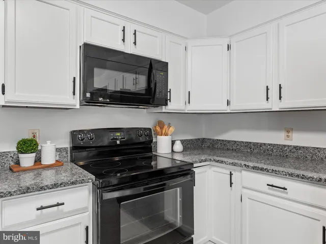 a kitchen with stainless steel appliances granite countertop white cabinets a stove a sink and dishwasher