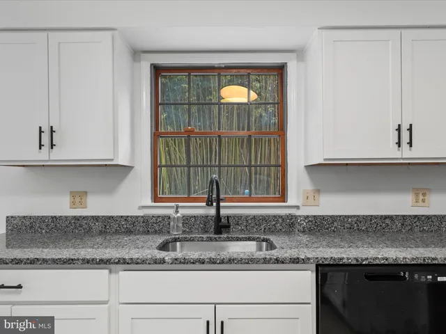 a kitchen with granite countertop a sink and cabinets