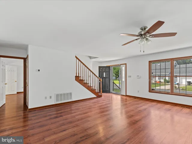 a view of an empty room with window and wooden floor