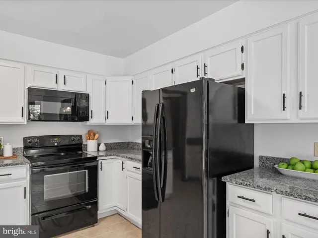 a kitchen with granite countertop a refrigerator and a stove top oven