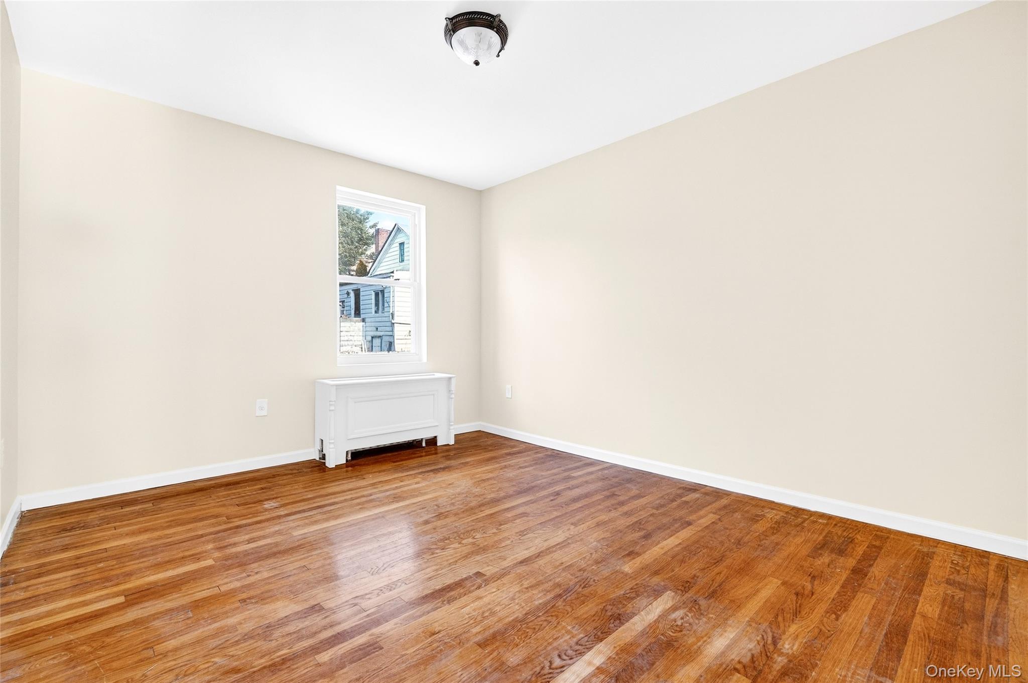 989 Sacket Avenue Bronx, NY 10462 - Photo 11 of 29 an empty room with wooden floor and windows