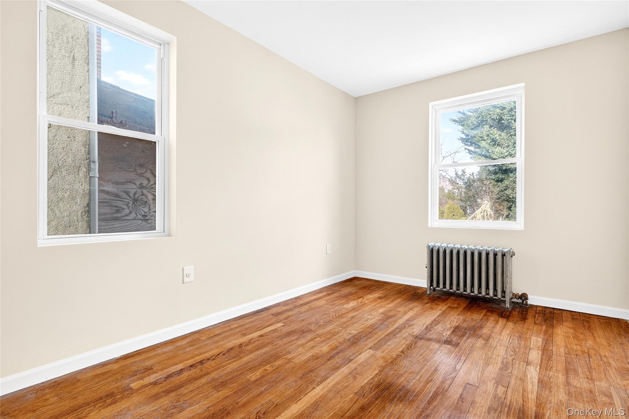 989 Sacket Avenue Bronx, NY 10462 - Photo 14 of 29 an empty room with wooden floor and windows