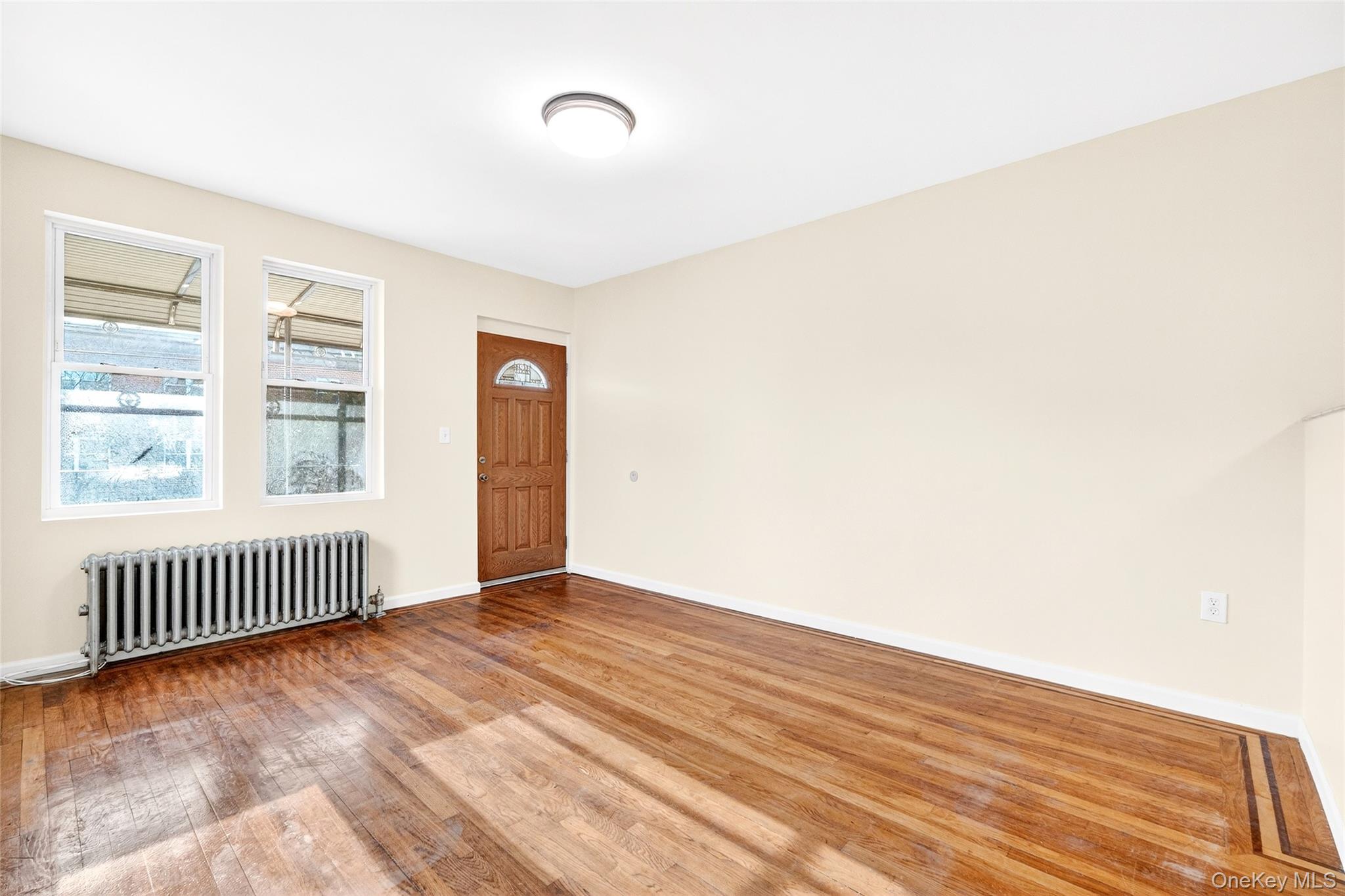 989 Sacket Avenue Bronx, NY 10462 - Photo 5 of 29 an empty room with wooden floor and windows