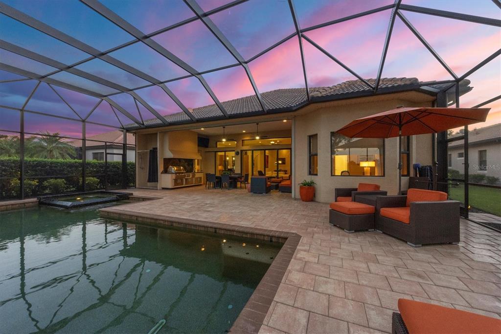 14519 Leopard Creek Place Lakewood Ranch, FL 34202 - Photo 6 of 56 a view of a patio with a table and chairs under an umbrella
