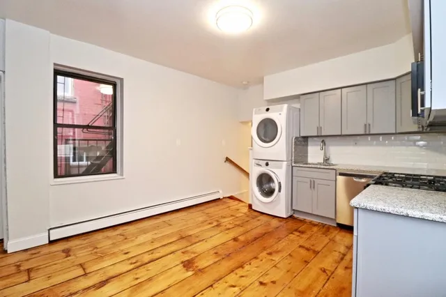 a kitchen with a stove top oven sink and wooden floor