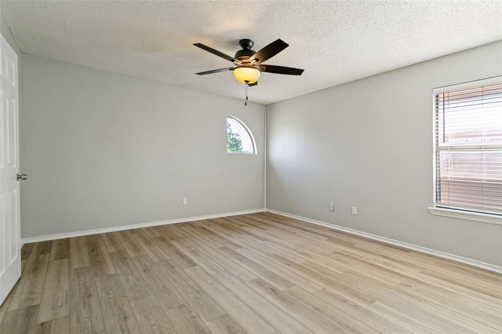 1712 East Peters Colony Road Carrollton, TX 75007 - Photo 19 of 25 Spacious room featuring wood-finish flooring, light gray walls, a ceiling fan with integrated lighting, a rectangular window with blinds, and an arched window