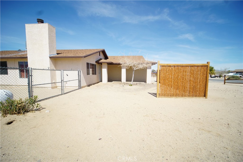4818 Round Up Road Twentynine Palms, CA 92277 - Photo 21 of 25 a view of a white house with wooden fence