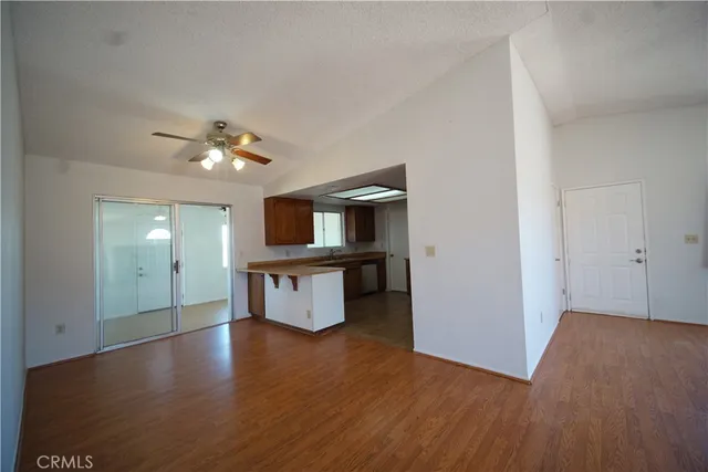 a view of an empty room with a chandelier fan and wooden floor