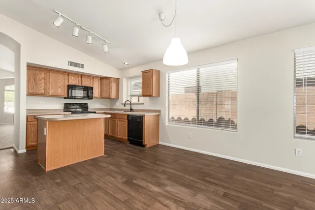 a kitchen with stainless steel appliances granite countertop a sink a stove a refrigerator cabinets and a large window