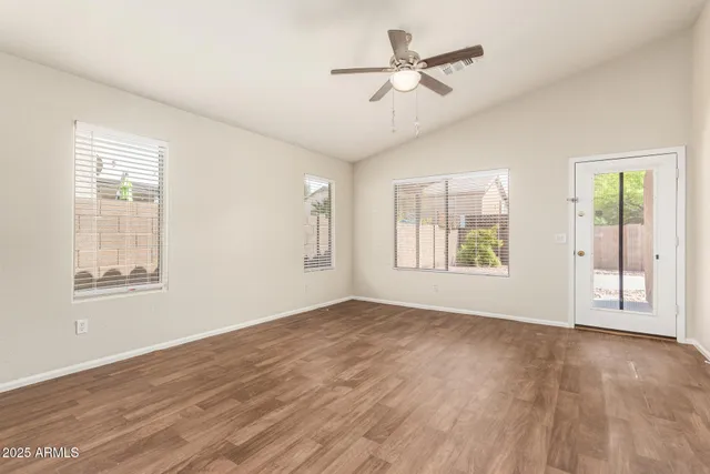 a view of an empty room with a window and wooden floor