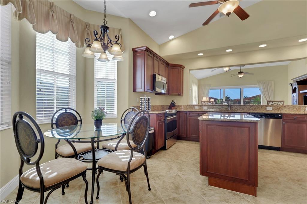 6397 Legacy Circle, Unit 2003 Naples, FL 34113 - Photo 10 of 26 a kitchen with kitchen island granite countertop wooden cabinets and stainless steel appliances