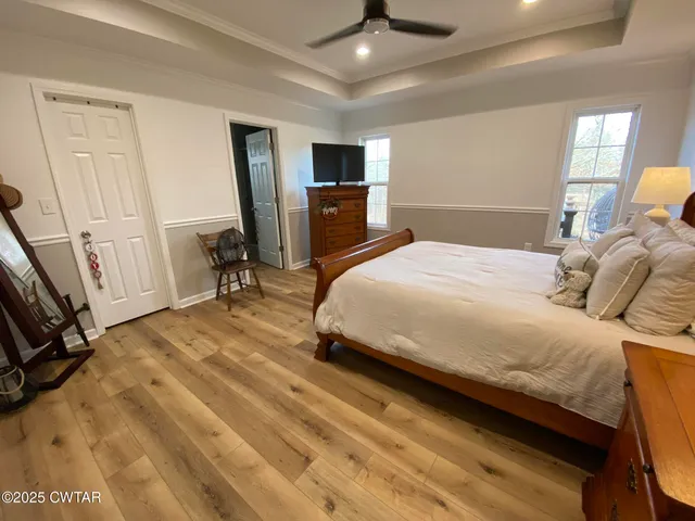 a bedroom with a bed a flat tv screen and dresser