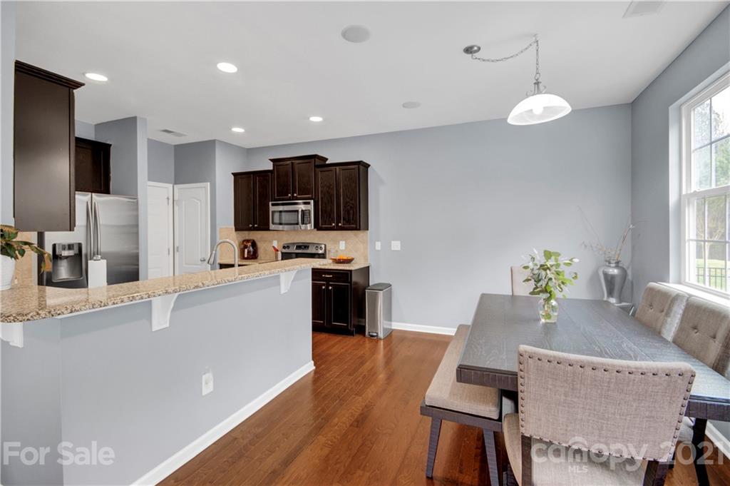 78174 Rillstone Drive Lancaster, SC 29720 - Photo 10 of 33 a kitchen with stainless steel appliances granite countertop a stove top oven a sink a dining table and chairs with wooden floor