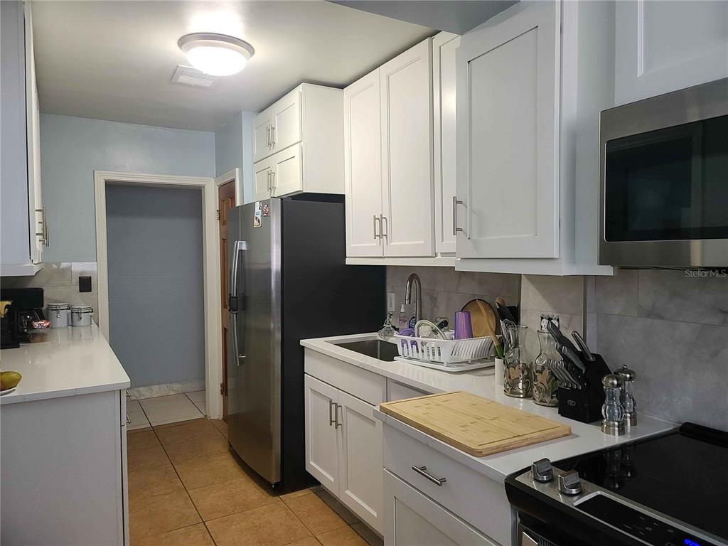 1187 Varnado Road Groveland, FL 34736 - Photo 22 of 25 a kitchen with stainless steel appliances a refrigerator sink and cabinets