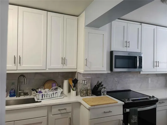 a kitchen with granite countertop white cabinets and black appliances