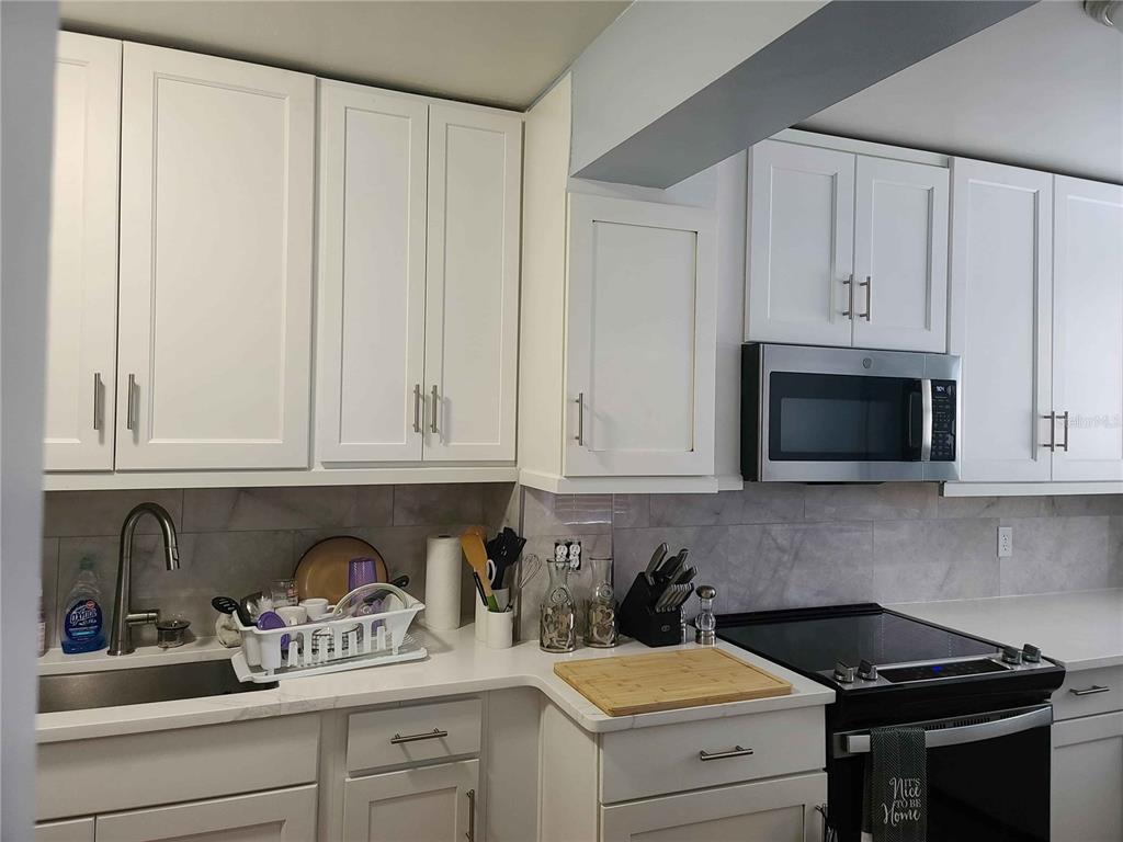 1187 Varnado Road Groveland, FL 34736 - Photo 24 of 25 a kitchen with granite countertop white cabinets and black appliances