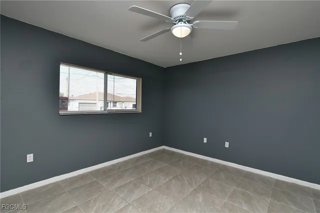 an empty room with a ceiling fan and a window