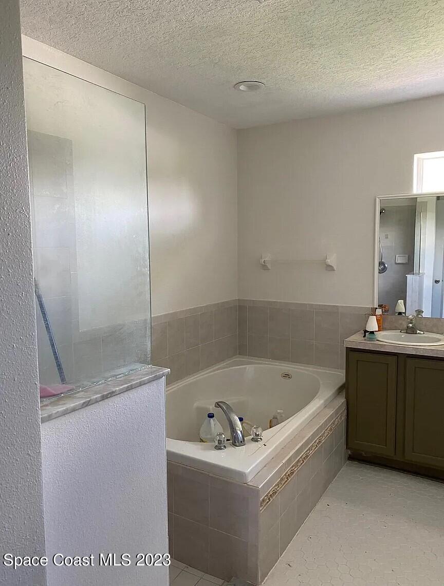 1913 Gloria Circle Palm Bay, FL 32905 - Photo 15 of 18 a bathroom with a bathtub a sink a vanity and a shower