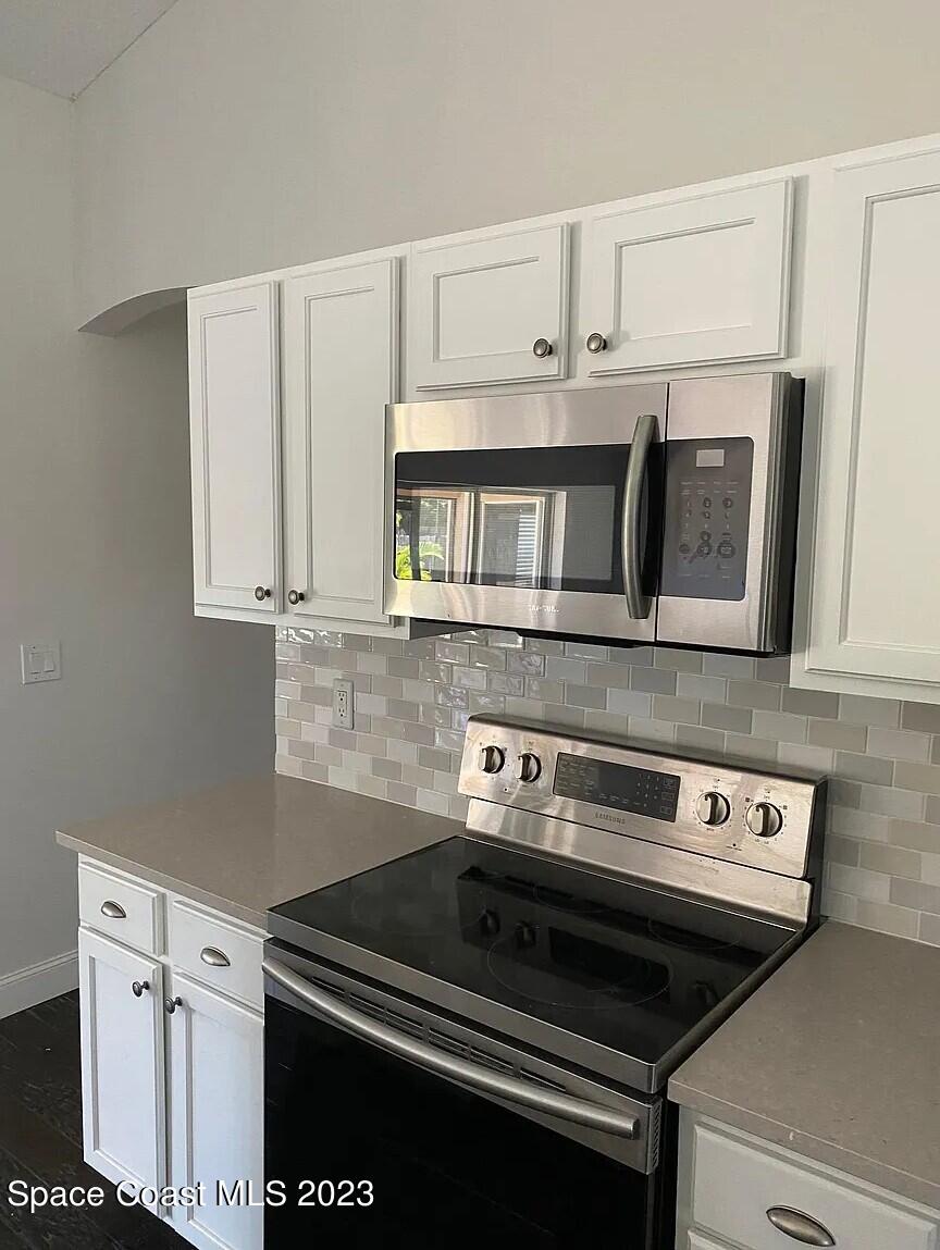 1913 Gloria Circle Palm Bay, FL 32905 - Photo 7 of 18 a kitchen with white cabinets and black appliances