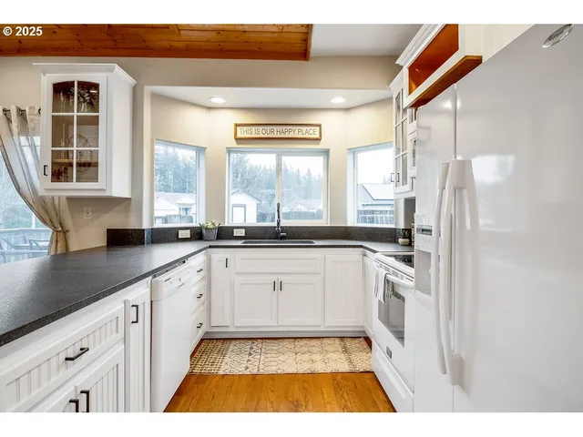 a large white kitchen with cabinets appliances and a window