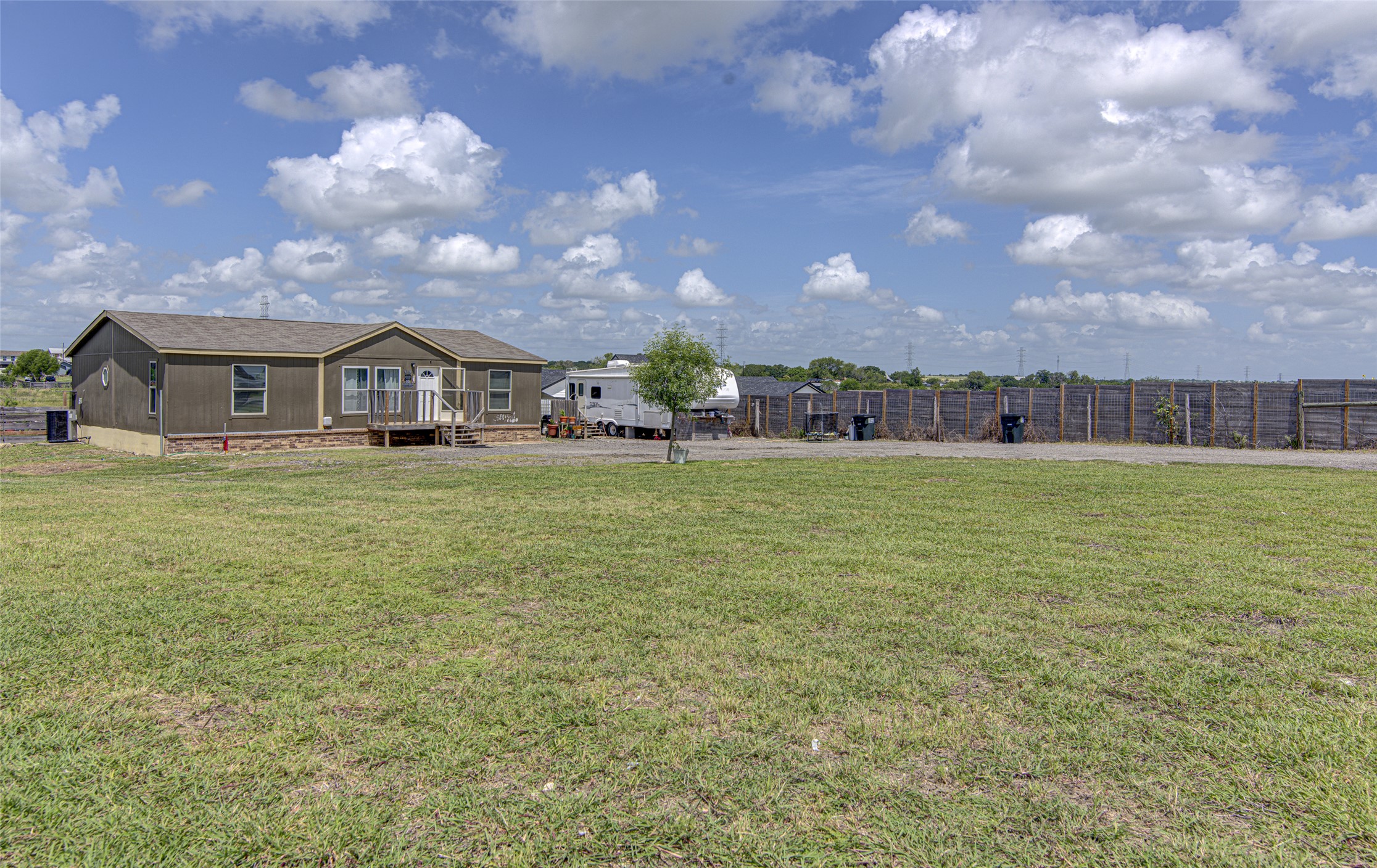 445 Rancho Linda Drive Lockhart, TX 78644 - Photo 4 of 26 A manufactured home with a spacious yard offers a comfortable and practical living experience.