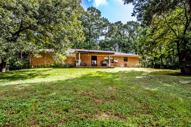 a view of house with a big yard and large trees