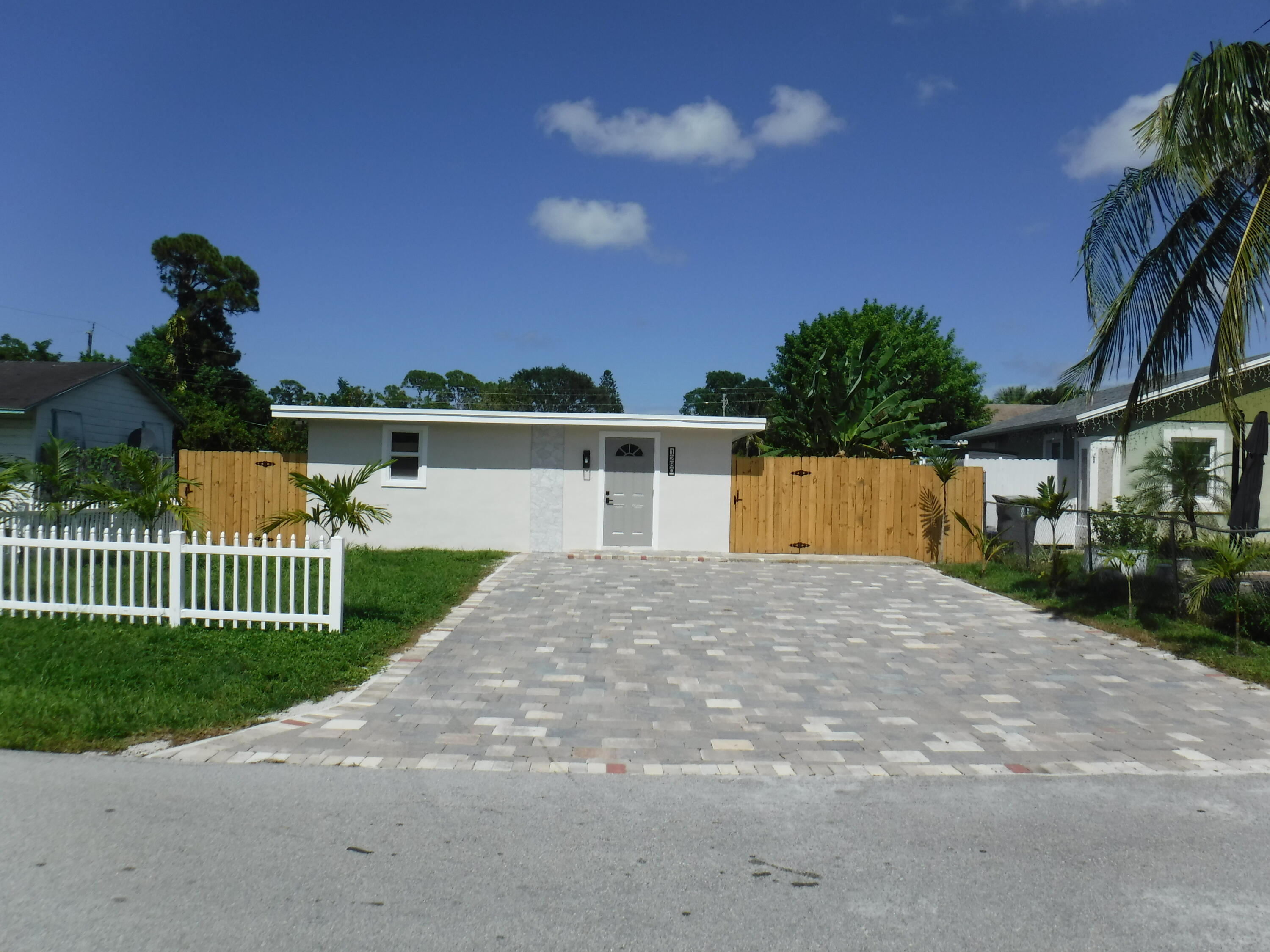 1280 Sunset Road West Palm Beach, FL 33406 - Photo 2 of 24 a front view of a house with a garden and yard