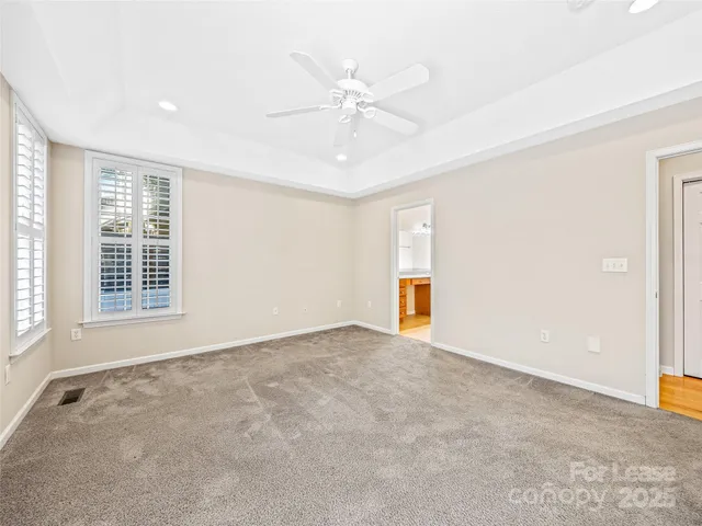 an empty room with windows and ceiling fan