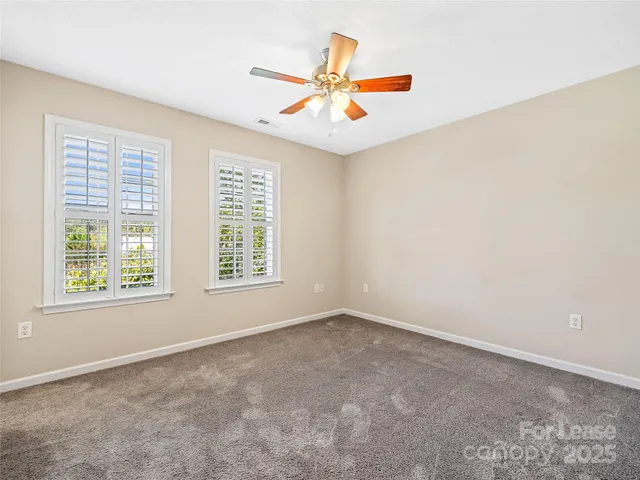 an empty room with ceiling fan and window