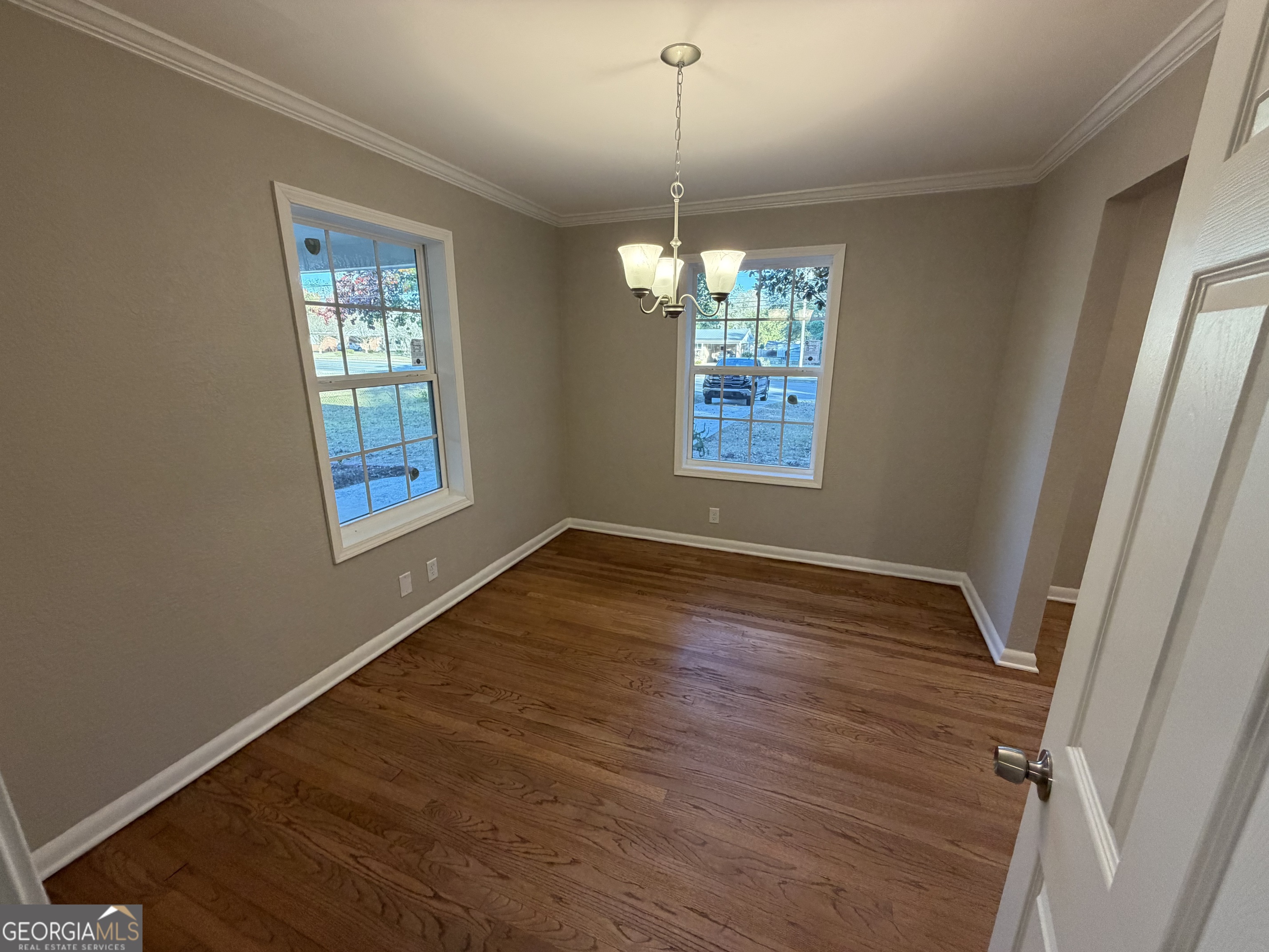116 Country Club Road Dublin, GA 31021 - Photo 13 of 22 an empty room with wooden floor chandelier and windows