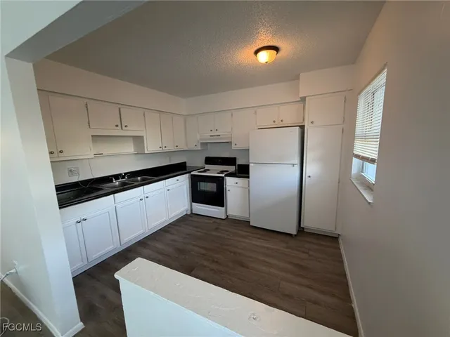 a kitchen with granite countertop a refrigerator sink and cabinets