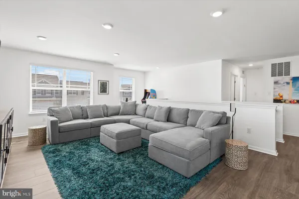 a living room with couches and kitchen view with wooden floor