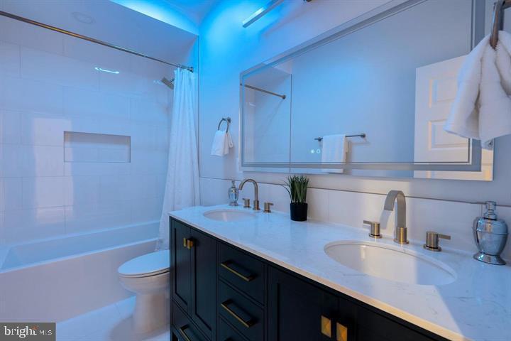 525 Kennedy Street Northwest, Unit 1 Washington, DC 20011 - Photo 21 of 27 a bathroom with a granite countertop sink toilet a mirror and bathtub