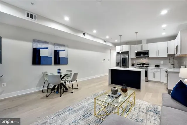 a living room with stainless steel appliances furniture and a kitchen view