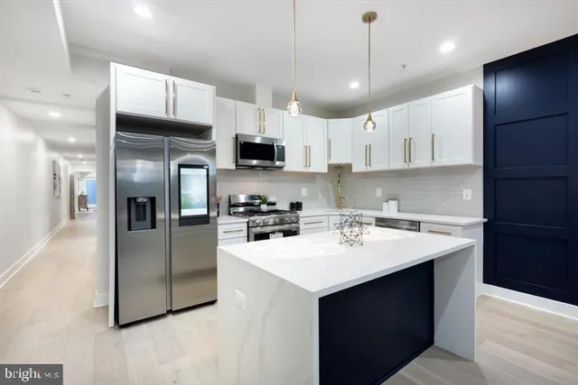 a kitchen with stainless steel appliances a sink a stove a refrigerator and cabinets