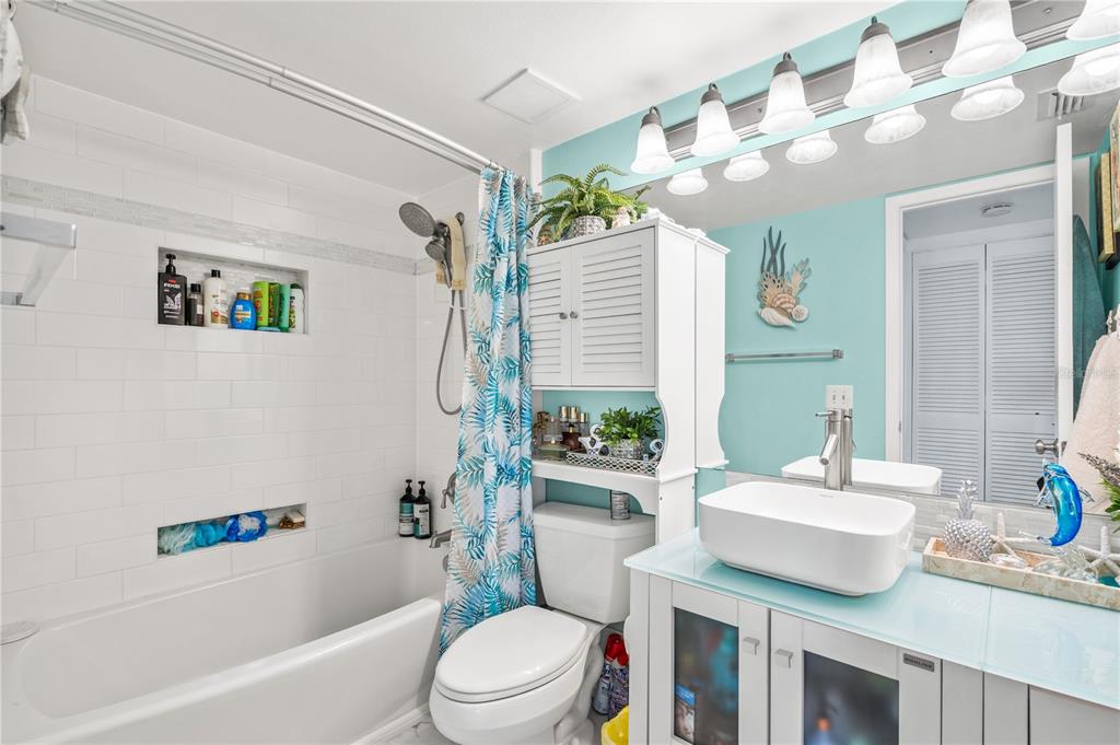 5722 Biscayne Court, Unit 308 New Port Richey, FL 34652 - Photo 16 of 31 a bathroom with a sink a toilet a mirror a vanity a bath tub and shower