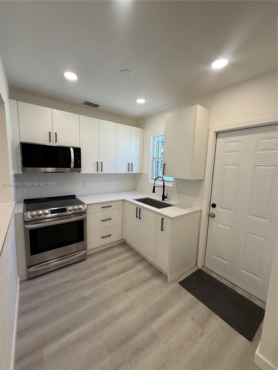 4020 Northwest 12th Avenue Miami, FL 33142 - Photo 3 of 13 a kitchen with a white stove top oven and white cabinets